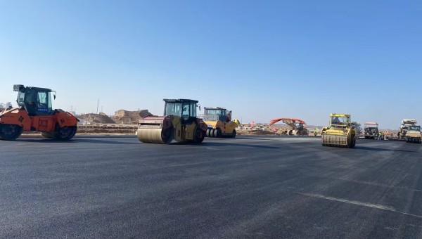 近日，在西部市政建設(shè)集團(tuán)蘭州新區(qū)城市礦產(chǎn)與表面處理產(chǎn)業(yè)園區(qū)（二期）周邊基礎(chǔ)設(shè)施項(xiàng)目—園區(qū)西路南延段（緯五十路至緯二十八路）項(xiàng)目現(xiàn)場(chǎng)，隨著一輛輛運(yùn)料車平穩(wěn)駛?cè)耄瑪備仚C(jī)將滾燙的瀝青混合料均勻鋪開，標(biāo)志著項(xiàng)